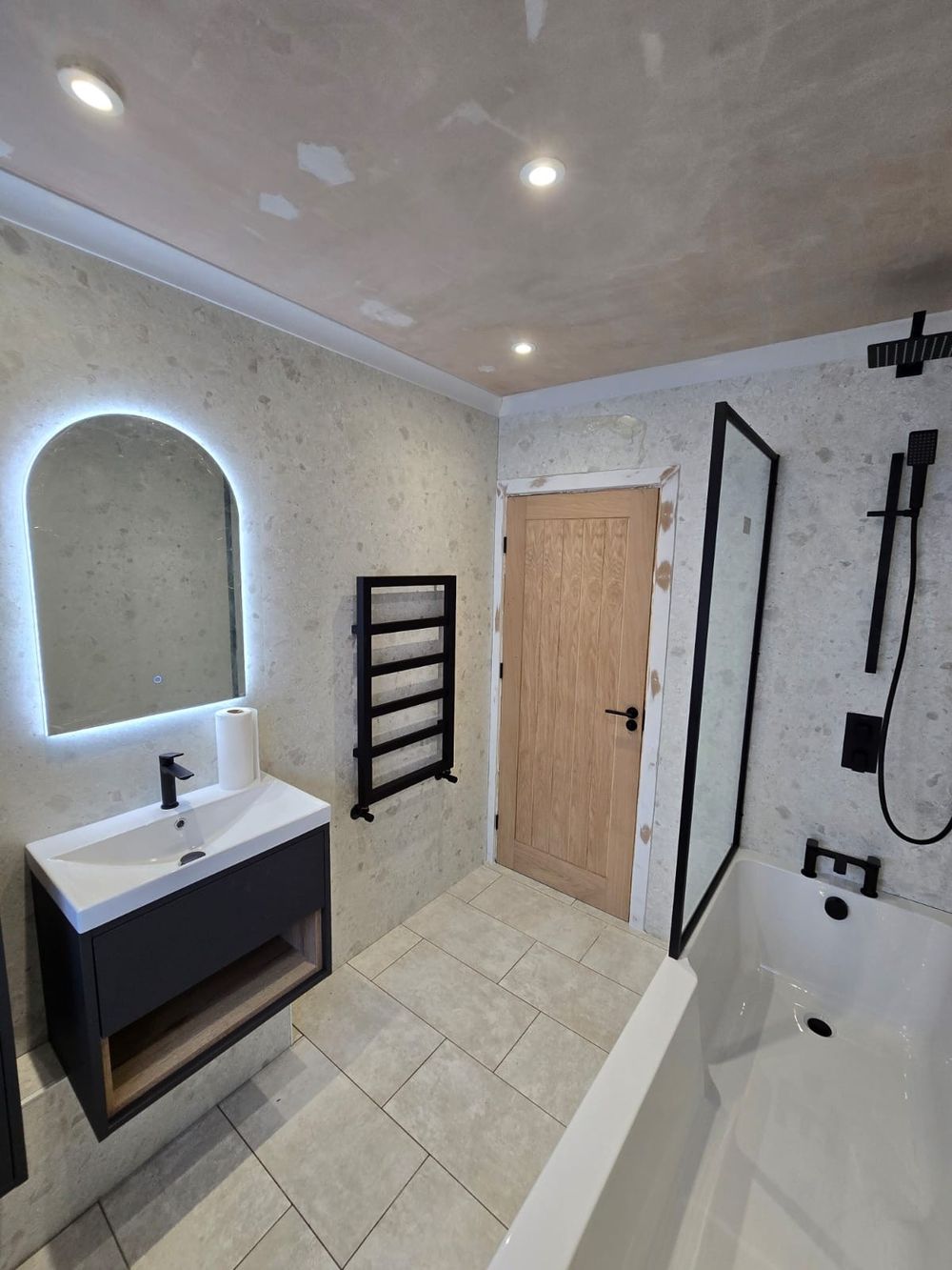 Renovated bathroom with black fixtures and oak door