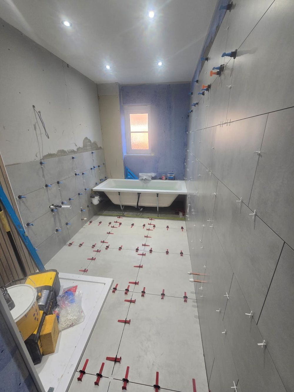 Bathroom wall and floor tiling in progress with levelling clips