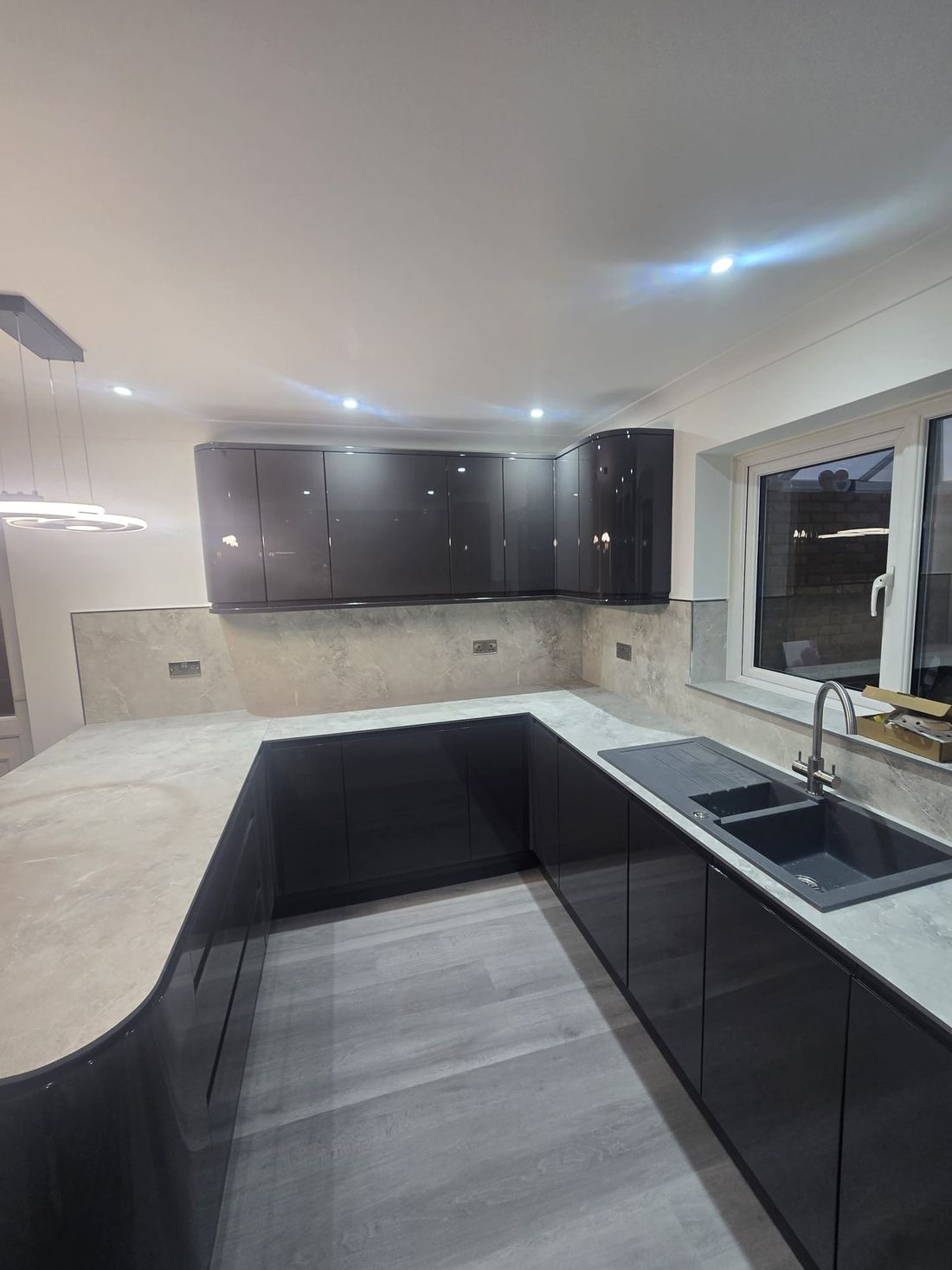 U-shaped gloss kitchen with stone splashback